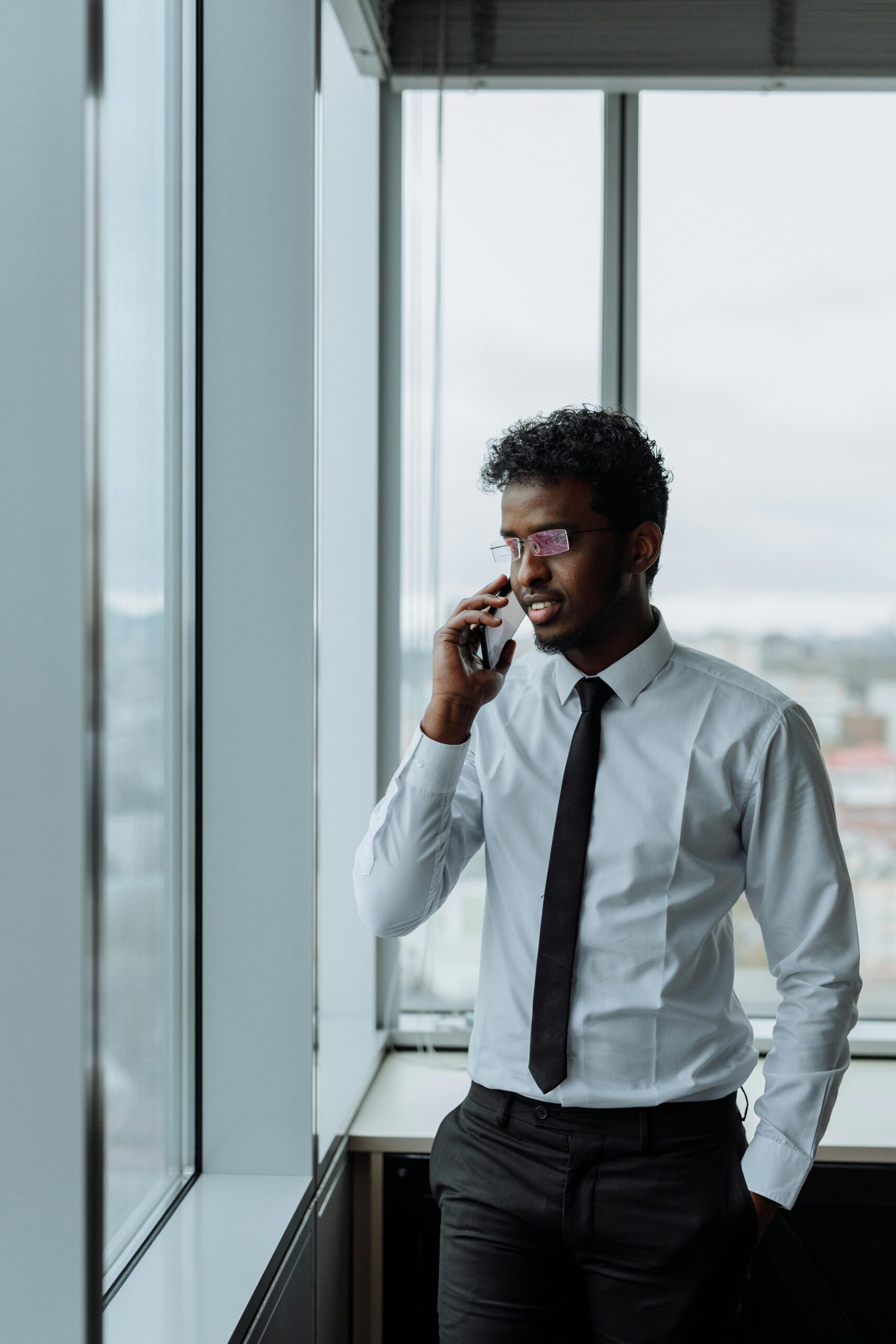 Professional South Asian businessman speaking on phone in modern office setting.